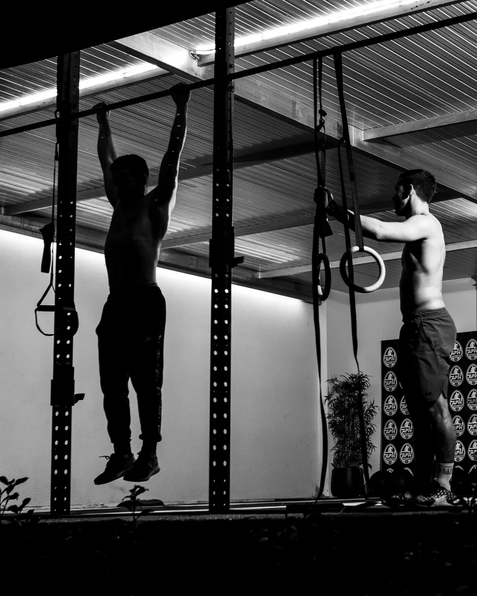 Atletas haciendo dominadas y anillas en Cross Box APH, en blanco y negro