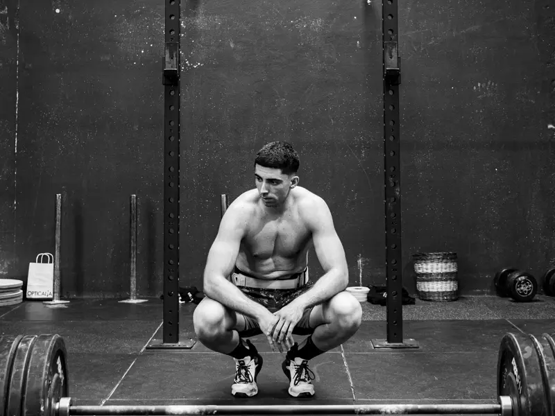 Atleta de Cross Box APH agachado frente al rack, concentrándose antes de levantar la barra