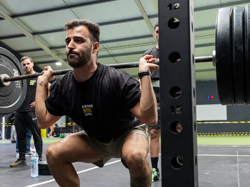Atleta de Cross Box APH haciendo sentadilla con barra en el rack en APH Games